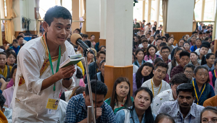 A member of the audience asking His Holiness the Dalai Lama a question during an intermission on the first day of teachings for young Tibetan students at the Main Tibetan Temple in Dharamsala, HP, India on June 6, 2018. Photo by Tenzin Phuntsok A member of the audience asking His Holiness the Dalai Lama a question during an intermission on the first day of teachings for young Tibetan students at the Main Tibetan Temple in Dharamsala, HP, India on June 6, 2018. Photo by Tenzin Phuntsok