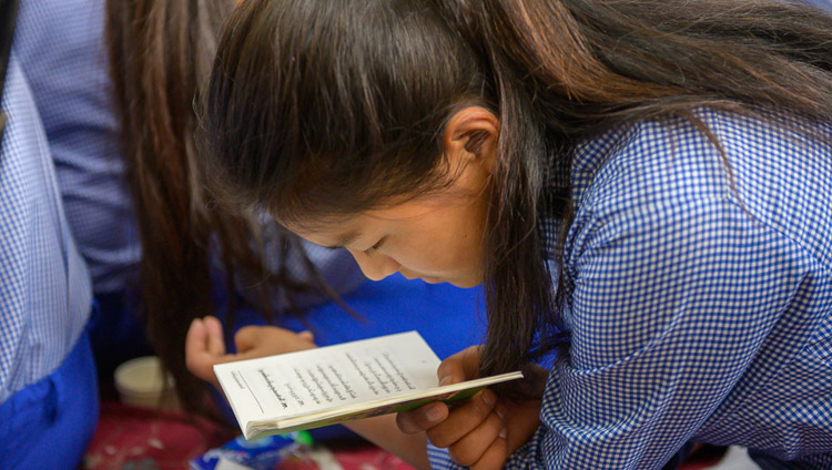A Tibetan student from Tibetan Children’s Village (TCV) school looking at the text during His Holiness the Dalai Lama's teaching at the Main Tibetan Temple in Dharamsala, HP, India on June 3, 2019. Photo by Tenzin Choejor A Tibetan student from Tibetan Children’s Village (TCV) school looking at the text during His Holiness the Dalai Lama's teaching at the Main Tibetan Temple in Dharamsala, HP, India on June 3, 2019. Photo by Tenzin Choejor