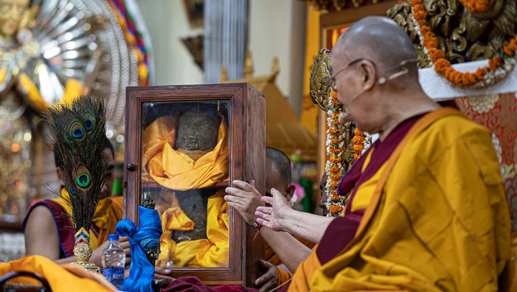 His Holiness the Dalai Lama gesturing at a glass case containing pieces of an Avalokiteshvara statue destroyed during the cultural revolution but later rescued and brought to India as he explains the Avalokiteshvara Empowerment at the Main Tibetan Temple in Dharamsala, HP, India on June 5, 2019. Photo by Tenzin Choejor His Holiness the Dalai Lama gesturing at a glass case containing pieces of an Avalokiteshvara statue destroyed during the cultural revolution but later rescued and brought to India as he explains the Avalokiteshvara Empowerment at the Main Tibetan Temple in Dharamsala, HP, India on June 5, 2019. Photo by Tenzin Choejor