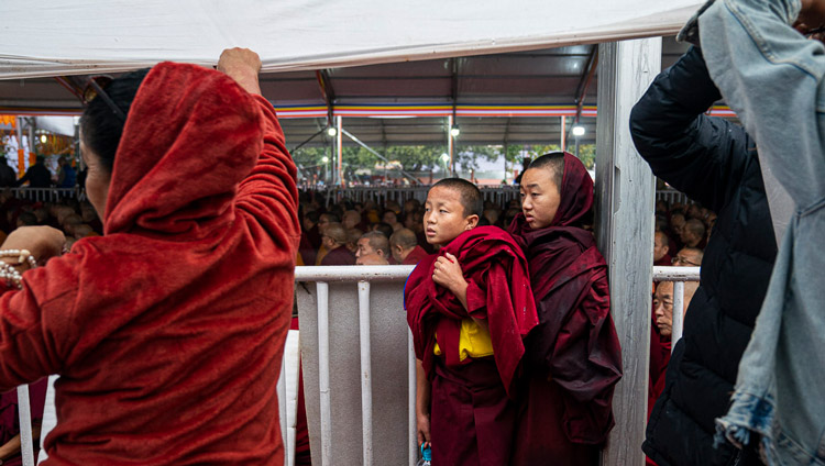 Young monks finding protection from the rain during as His Holiness the Dalai Lama addresses the crowd before conducting an Avalokiteshvara Empowerment at the Kalachakra Ground in Bodhgaya, Bihar, India on January 3, 2020. Photo by Tenzin Choejor Young monks finding protection from the rain during as His Holiness the Dalai Lama addresses the crowd before conducting an Avalokiteshvara Empowerment at the Kalachakra Ground in Bodhgaya, Bihar, India on January 3, 2020. Photo by Tenzin Choejor