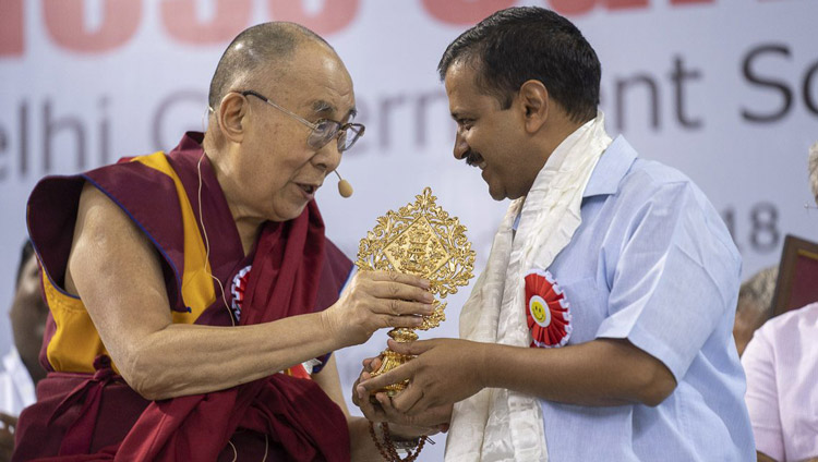 His Holiness the Dalai Lama presenting Delhi Chief Minister Arvind Kejriwal with an auspicious emblem at the conclusion of the launch of the Happiness Curriculum in Delhi Government Schools at Thyagraj Stadium in New Delhi, India on July 2, 2018. Photo by Tenzin Choejor His Holiness the Dalai Lama presenting Delhi Chief Minister Arvind Kejriwal with an auspicious emblem at the conclusion of the launch of the Happiness Curriculum in Delhi Government Schools at Thyagraj Stadium in New Delhi, India on July 2, 2018. Photo by Tenzin Choejor