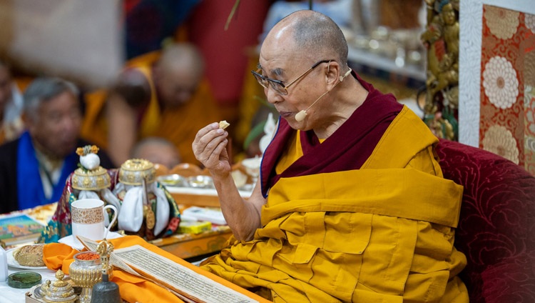 His Holiness the Dalai Lama taking a quick break in the preliminary practices for the Avalokiteshvara Empowerment to enjoy some bread on the second day of his Teachings for Tibetan Youth at the Main Tibetan Temple in Dharamsala, HP, India on June 2, 2022. Photo by Tenzin Choejor His Holiness the Dalai Lama taking a quick break in the preliminary practices for the Avalokiteshvara Empowerment to enjoy some bread on the second day of his Teachings for Tibetan Youth at the Main Tibetan Temple in Dharamsala, HP, India on June 2, 2022. Photo by Tenzin Choejor