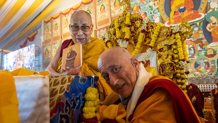 Ratö Khensur, Nicholas Vreeland, presenting His Holiness the Dalai Lama with the first copy of a newly published book that contains His Holiness’s spiritual biography composed by the late Ratö Khyongla Rinpoché at the start of the second day of teachings in Bodhgaya, Bihar, India on December 30, 2022. Photo by Tenzin Choejor Ratö Khensur, Nicholas Vreeland, presenting His Holiness the Dalai Lama with the first copy of a newly published book that contains His Holiness’s spiritual biography composed by the late Ratö Khyongla Rinpoché at the start of the second day of teachings in Bodhgaya, Bihar, India on December 30, 2022. Photo by Tenzin Choejor